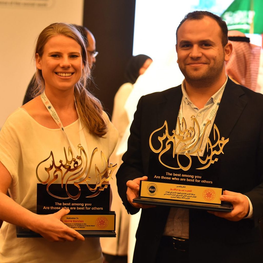 Two Piozone representatives holding engraved award plaques at the International Conference for Excellence in Social Work, Bahrain, 2019
